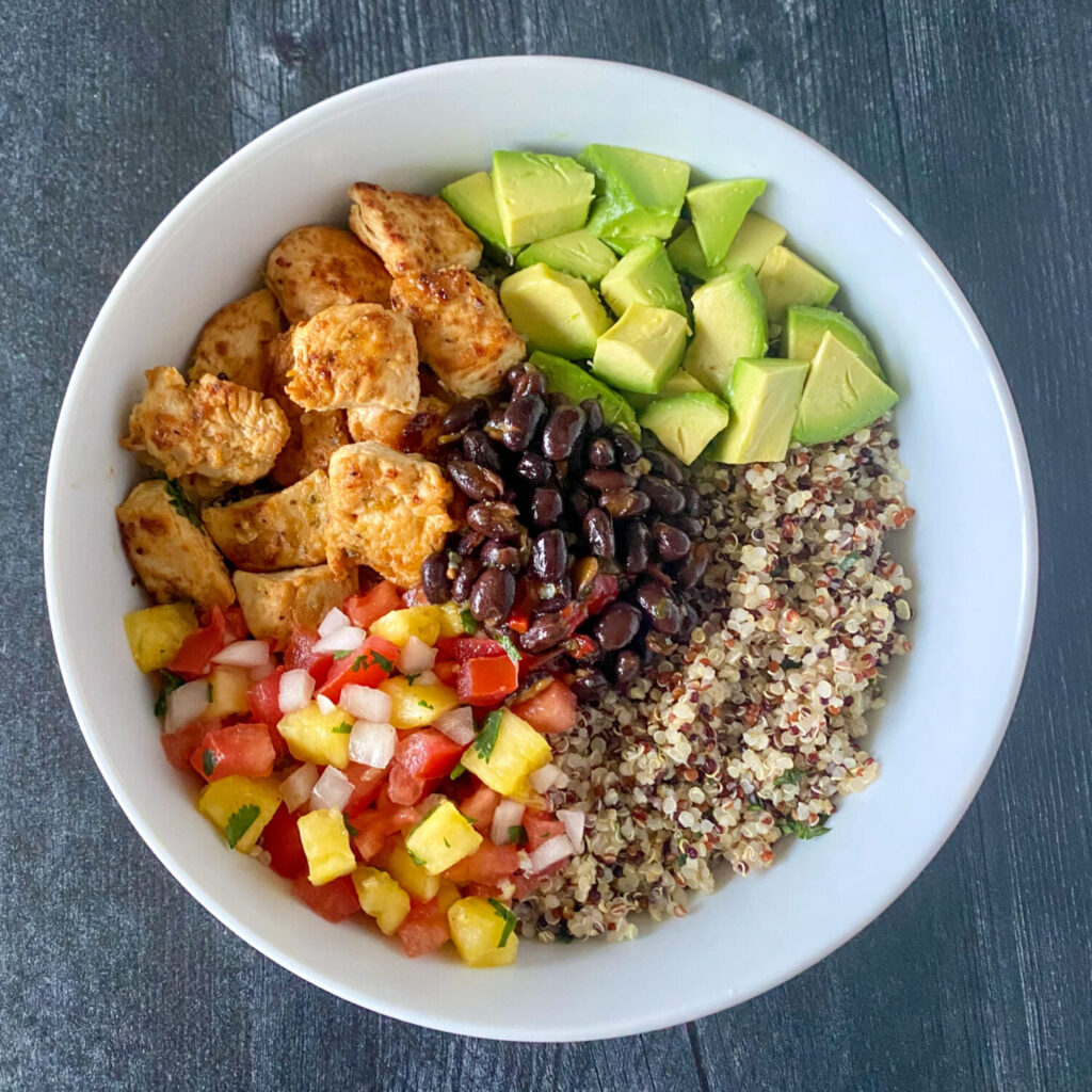Mojo Chicken, black beans, cilantro lime quinoa, pineapple pico de gallo and avocado in a white bowl