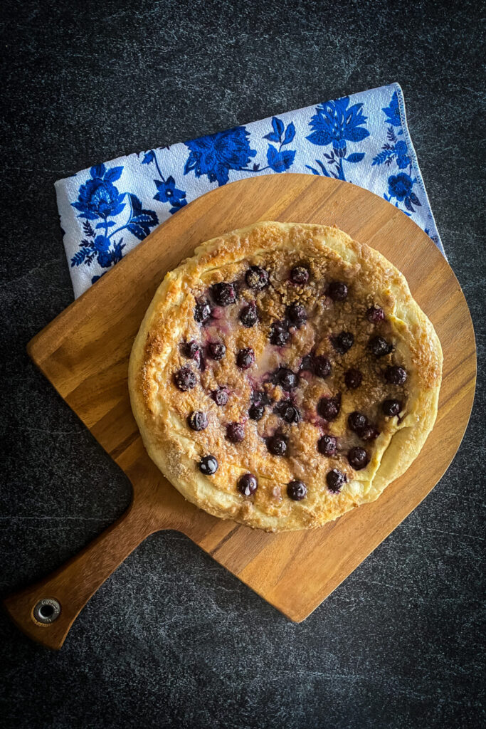 Blueberry breakfast pizza with cream cheese, streusel topping and fresh blueberries drizzled with a powdered sugar glaze